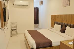 1 dormitorio con 1 cama grande y 1 silla en Hotel Shree Meghdootam, en Bhopal