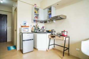a small kitchen with a white refrigerator and a table at Urban Oasis Condo Near Ayala Centrio in Cagayan de Oro