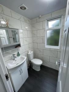 a bathroom with a toilet and a sink and a window at Luxurious & Spacious Apartment with PARKING close to LONDON in Harold Wood