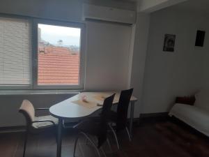 a room with a table and chairs and a window at Prostrani apartman Cacak in Čačak