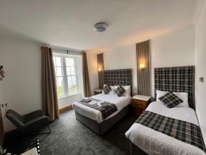 a hotel room with two beds and a chair at The Grey Gull Hotel in Ardrishaig