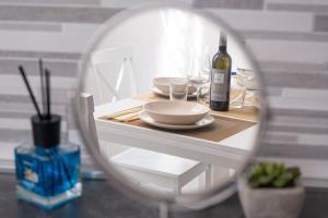 una mesa con platos y una botella de vino y un espejo en [Twins apartament Giallo]clima en Génova