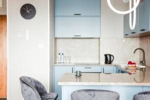 a kitchen with blue cabinets and bar stools at Apartamenty Blue in Biała Podlaska