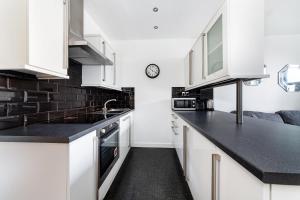 a kitchen with white cabinets and black counter tops at McLaren House Seahouses in Seahouses