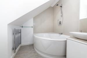 a white bathroom with a sink and a tub at McLaren House Seahouses in Seahouses