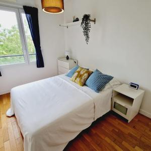 a white bedroom with a bed and a window at Modern and confortable apartment close to Paris in Bois-Colombes
