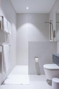 La salle de bains blanche est pourvue de toilettes et d'un lavabo. dans l'établissement Casa Flurina, à Flims