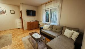 ein Wohnzimmer mit einem Sofa und einem TV in der Unterkunft Apartmani JELENA Opatija in Opatija