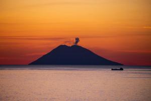 une petite île dans l'océan avec un coucher de soleil dans l'établissement Residence Praia di Fuoco, à Capo Vaticano