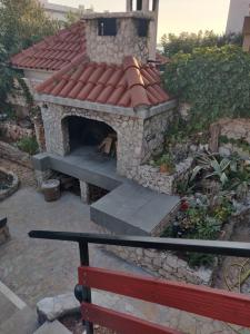 a stone fireplace with a red roof at Deni in Sevid