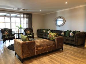een woonkamer met 2 banken en een tafel bij Romney Park Luxury Apartments in Kaapstad