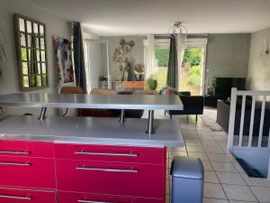 cocina con armarios rojos y sala de estar. en Agréables chambres dans maison suspendue, en Saint-Étienne