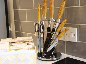 a group of utensils in a holder on a counter at Pass the Keys Heart of Llandovery Large 4BR Apartment For 9 in Llandovery