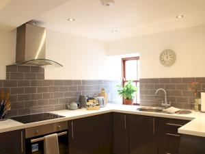 a kitchen with black cabinets and a sink and a clock at Pass the Keys Heart of Llandovery Large 4BR Apartment For 9 in Llandovery