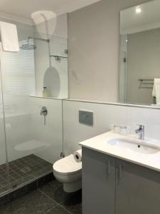 e bagno con servizi igienici, lavandino e doccia. di Romney Park Luxury Apartments a Città del Capo
