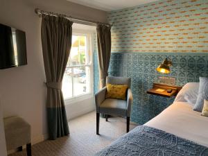 a bedroom with a bed and a chair and a window at The Bay Horse, Masham in Masham