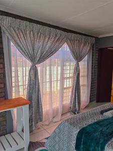 1 dormitorio con cama y ventana grande en Good and Proper Guest Lodge, en Vereeniging