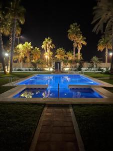 a large blue swimming pool at night with palm trees at MAGNIFICO CHALET UNICO JUNTO AL MAR CALETA DE VELEZ in Caleta De Velez