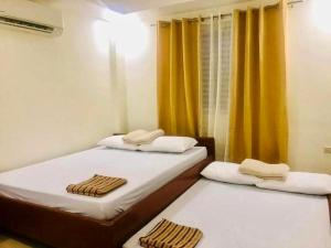 2 Einzelbetten in einem Zimmer mit gelben Vorhängen in der Unterkunft Charls Place - Private Villa with Pool for up to 20pax in Sablayan