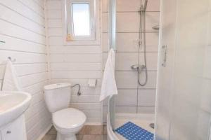 a white bathroom with a toilet and a shower at Comfortable and cozy holiday homes for 5 people Ch opy in Chłopy