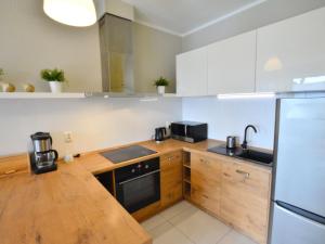 a kitchen with white cabinets and a wooden counter top at Cozy cottage for 2 people near the sandy beach in Pleśna