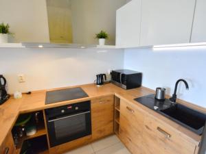 a kitchen with a stove and a sink and a microwave at Cozy cottage for 2 people near the sandy beach in Pleśna