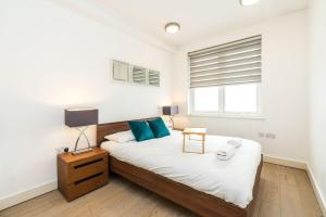 - une chambre avec un lit doté d'oreillers bleus et d'une fenêtre dans l'établissement Spacious 2 bedroom / Earls Court / Kensington, à Londres