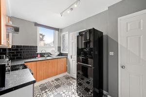 a kitchen with a black refrigerator and a sink at Contemporary apartment by train station and city centre in Kent