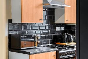 a kitchen with a stove and a microwave at Contemporary apartment by train station and city centre in Kent