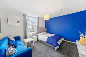 a blue bedroom with a bed and a blue wall at Contemporary apartment by train station and city centre in Kent