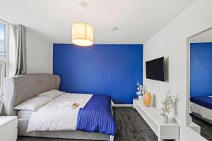 Dormitorio azul con cama y pared azul en Contemporary apartment by train station and city centre en Kent