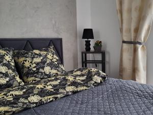 a bed with a black and white comforter and a lamp at Comfy apartment near the sea in G ski in Gąski