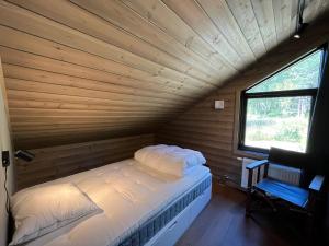 a bed in a wooden room with a window at Skarvruetstugan Funäsdalen in Tänndalen