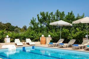 a swimming pool with lounge chairs and umbrellas at Villa Satra in Elefterna