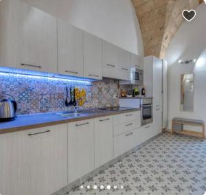 a kitchen with white cabinets and a tile floor at una volta al centro via roccamara in Nardò