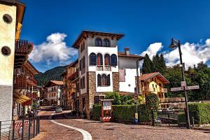 a large white building with a tower on a street at Nido Mountain Apartment in Castione della Presolana