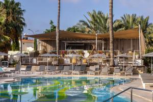 a pool with chairs and tables and a bar at King Jason Paphos - Designed for Adults by Louis Hotels in Paphos City