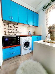 a kitchen with blue cabinets and a washing machine at Dani's boho home in Missolonghi