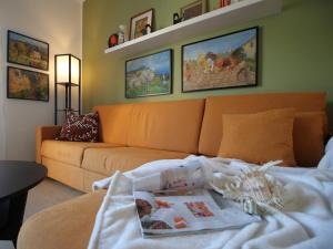a living room with an orange couch and some paintings at Il mare in Piazza in Albisola Superiore