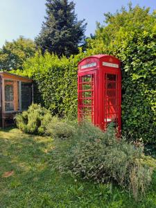 an old red phone booth in a garden at B&B Colorado in Bergamo