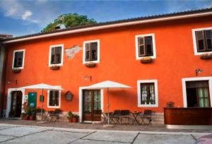 トリエステにあるHotel La Fontanaの目の前にテーブルと傘が置かれたオレンジ色の建物