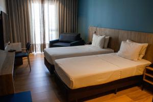 a hotel room with two beds and a chair at Hotel Senac Ilha do Boi in Vitória