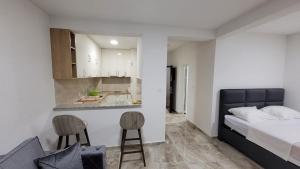 a bedroom with a bed and a kitchen with two chairs at Montenegro apartments Phoenix in Bar, Susanj