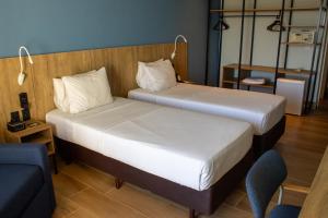 a hotel room with two beds and a chair at Hotel Senac Ilha do Boi in Vitória