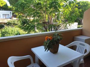 uma mesa branca com um vaso de flores numa varanda em ISA-Holiday Homes in Marina di Bibbona from 400 to 900 m from the beach em Marina di Bibbona