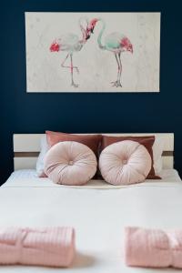 a bed with pink pillows and a painting of birds at Nice Apartment - Near Sky Tower - Private Parking in Wrocław