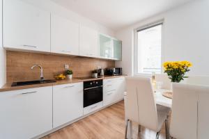 a kitchen with white cabinets and a sink and a table at Nice Apartment - Near Sky Tower - Private Parking in Wrocław