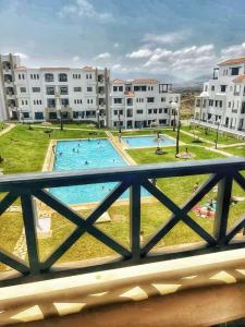 een uitzicht vanaf het balkon van een appartementencomplex met een zwembad bij Lilac's Garden vue piscine in M'diq