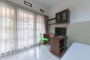 a bedroom with a desk with a computer and a green chair at KoolKost near BTC Fashion Mall 2 - Minimum Stay 30 Nights in Bandung
