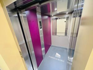 a glass elevator in a room with purple at TwoParrots app. with garage, balkony, citycenter in Žilina